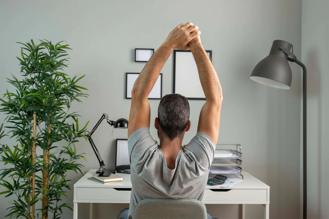 Professional performing desk stretches in modern office environment